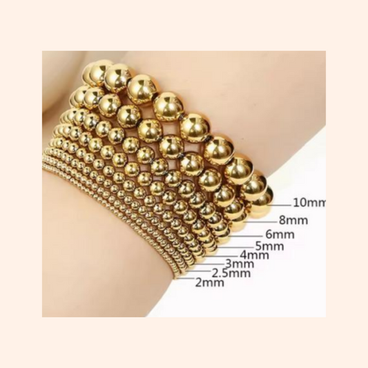 Gold beaded bracelet on a skin-toned surface with size measurements.