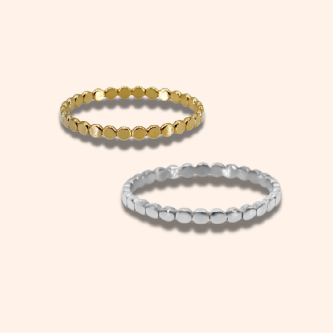 Two gold and silver beaded rings on a beige background