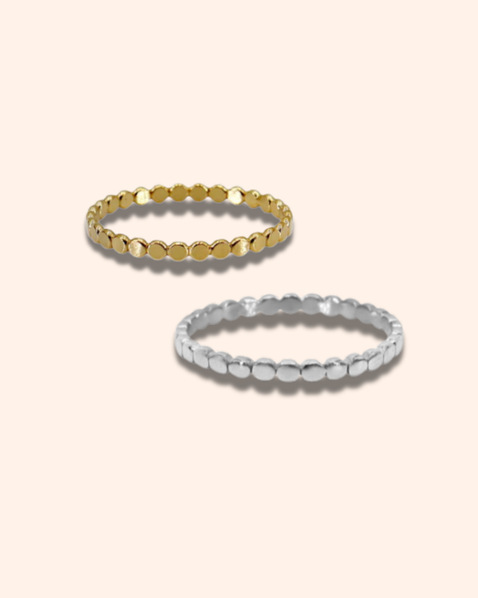 Two gold and silver beaded rings on a beige background