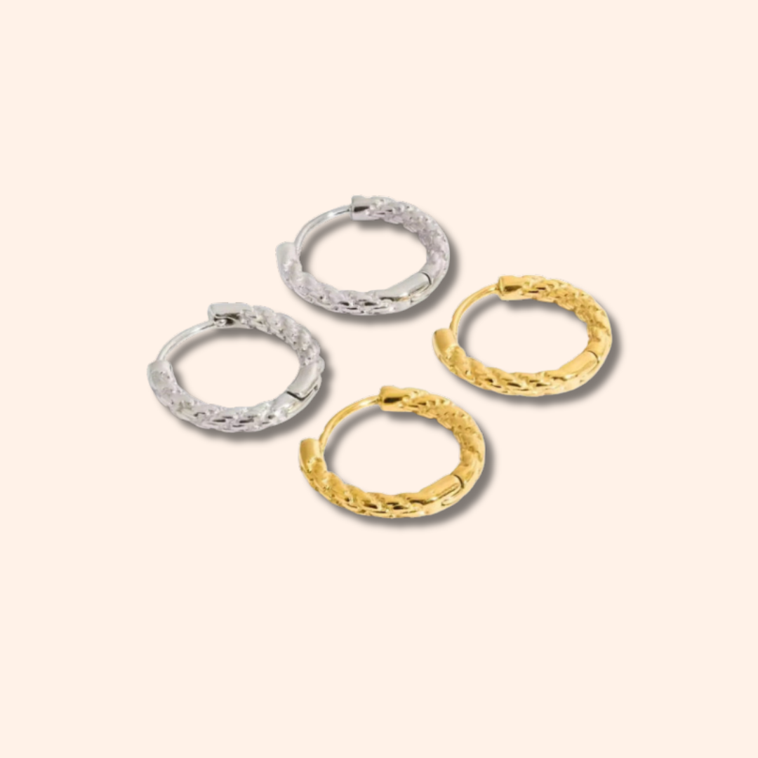 Four gold and silver hoop earrings on a light beige background