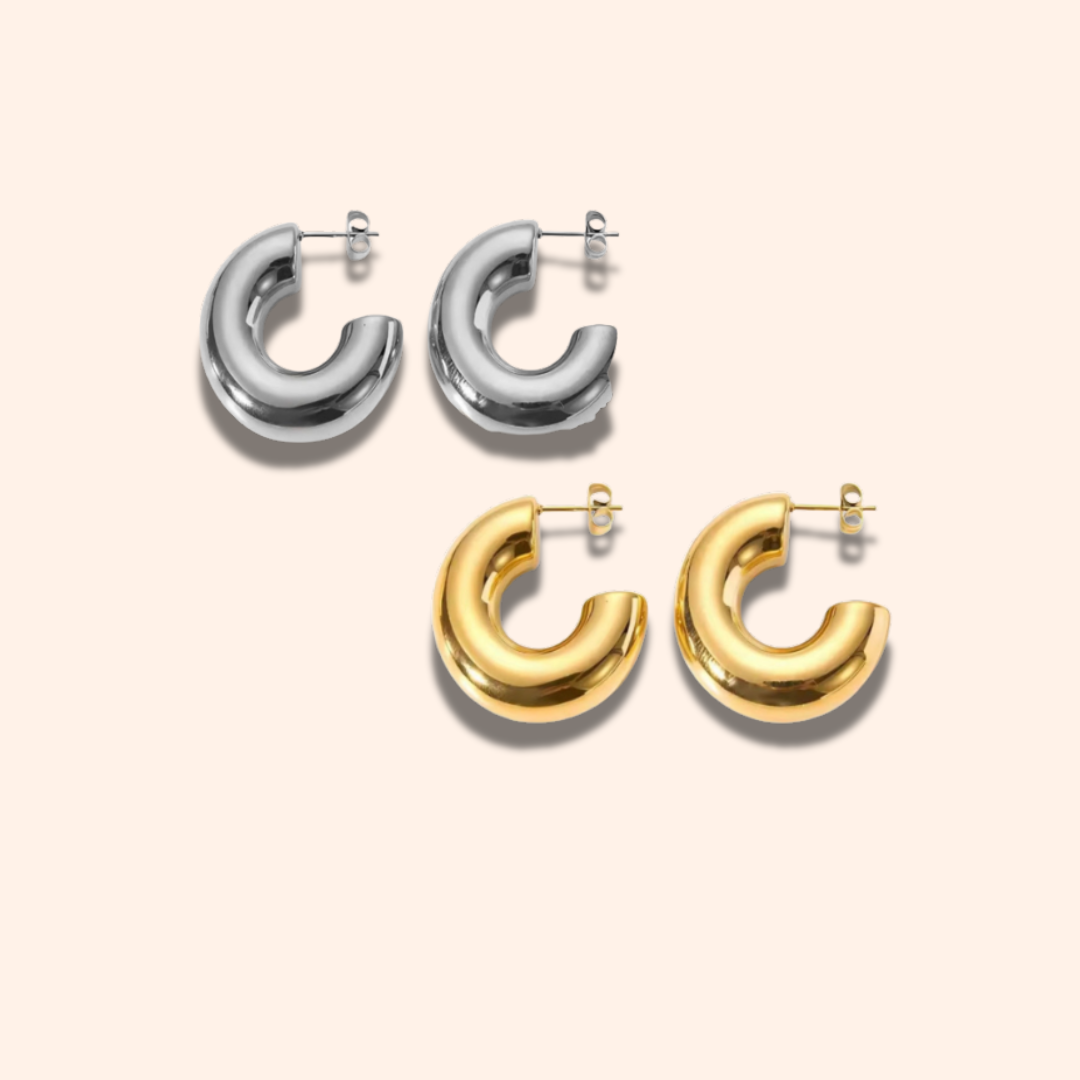 Pair of silver hoop earrings and pair of gold hoop earrings on a light beige background