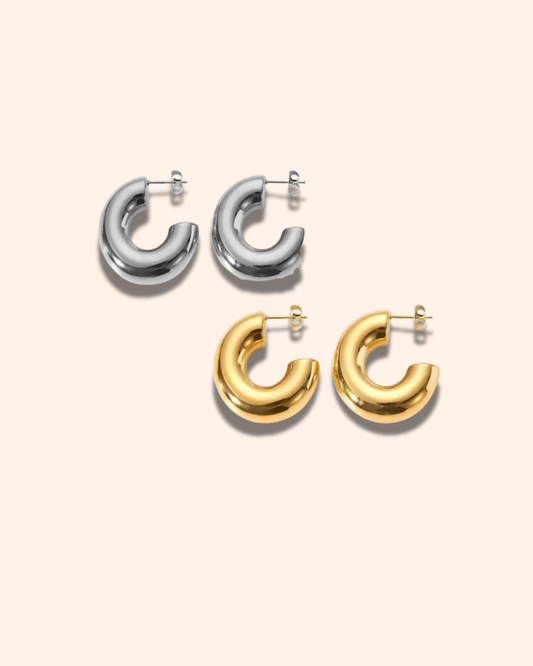 Pair of silver hoop earrings and pair of gold hoop earrings on a light beige background