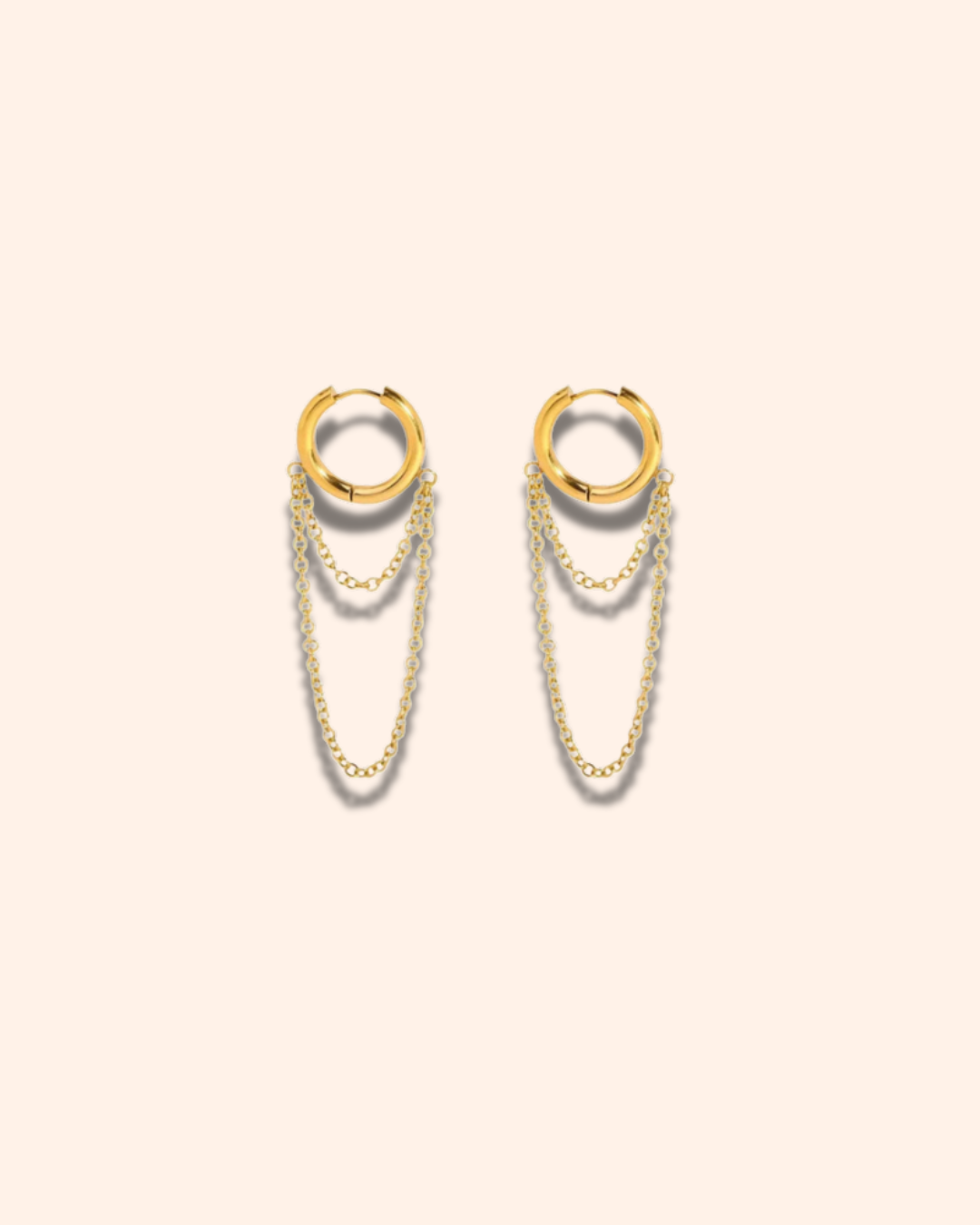 Gold hoop earrings with chains on a beige background