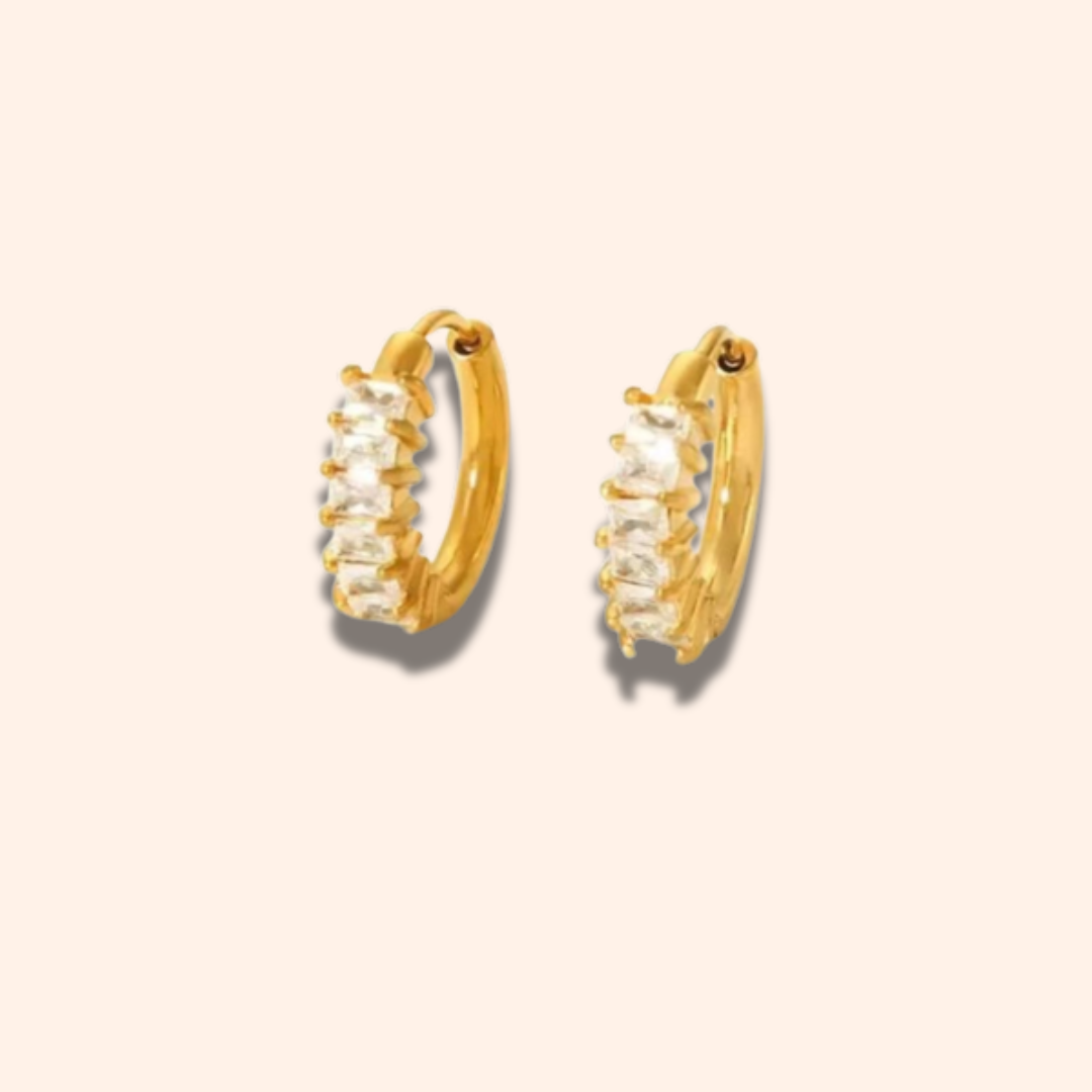 Gold hoop earrings with clear stones on a beige background