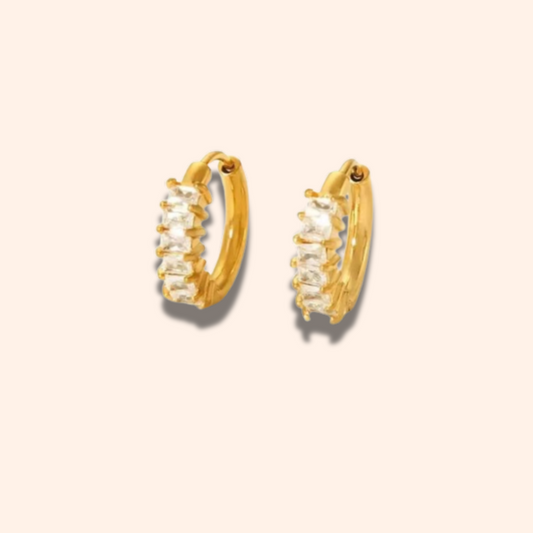 Gold hoop earrings with clear stones on a beige background