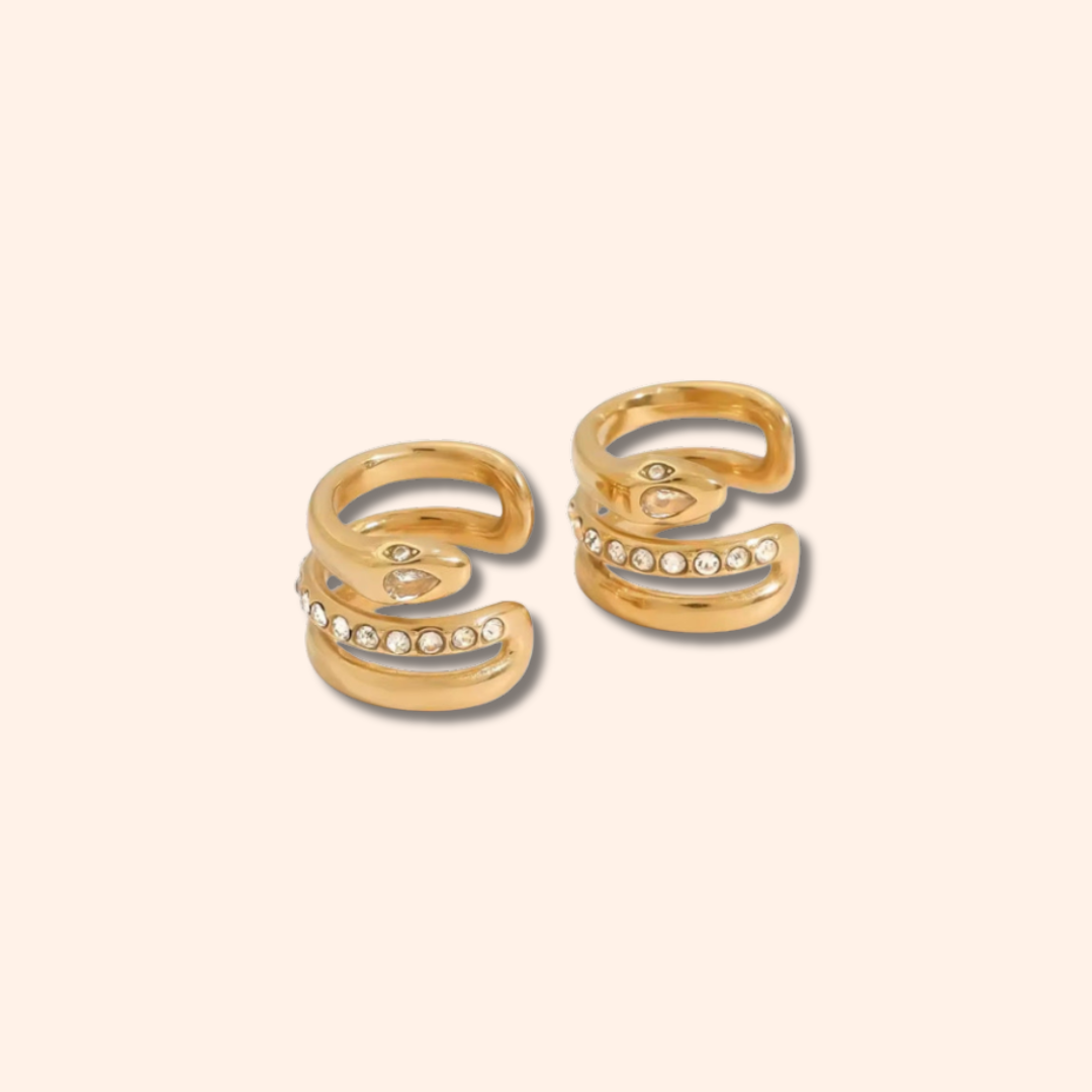Pair of gold open rings with small stones on a beige background