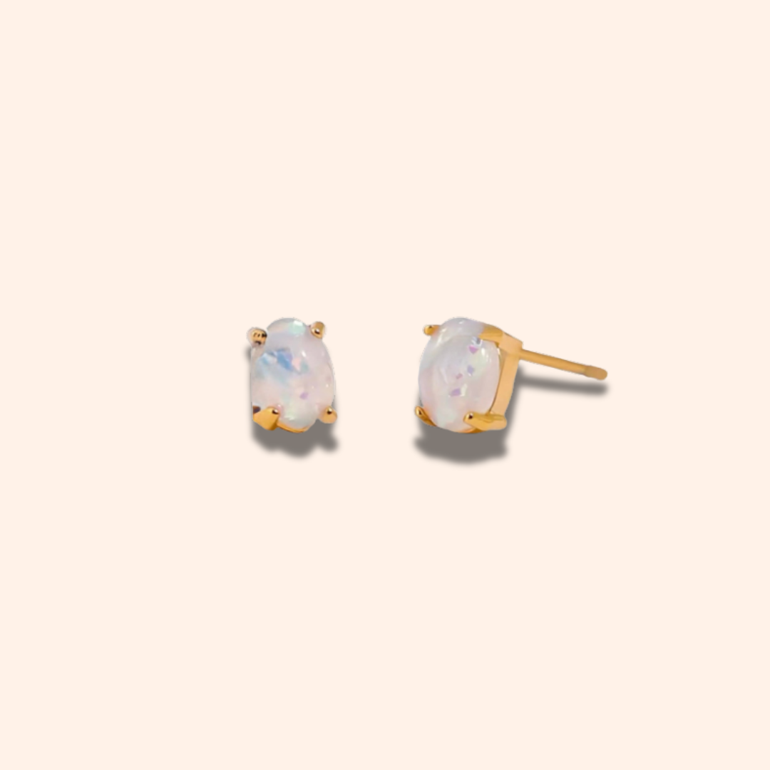 Pair of gold earrings with opal stones on a beige background