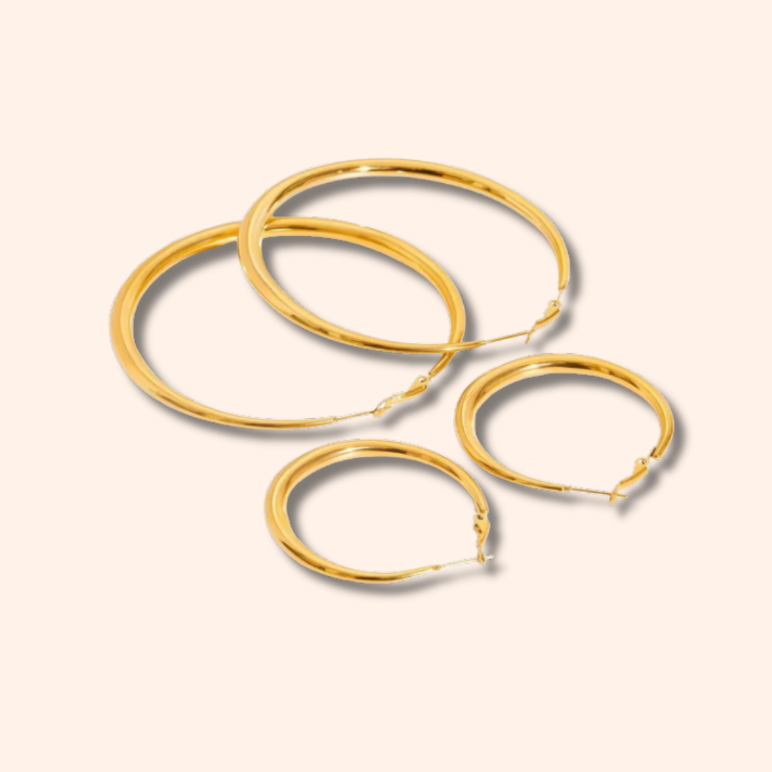 Set of gold hoop earrings on a beige background