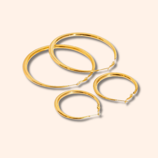 Set of gold hoop earrings on a beige background