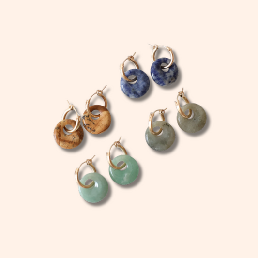 Set of earrings with various colored stones on a beige background