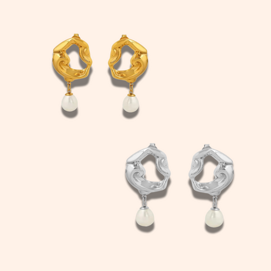 Pair of gold and silver earrings with pearl drops on a light pink background