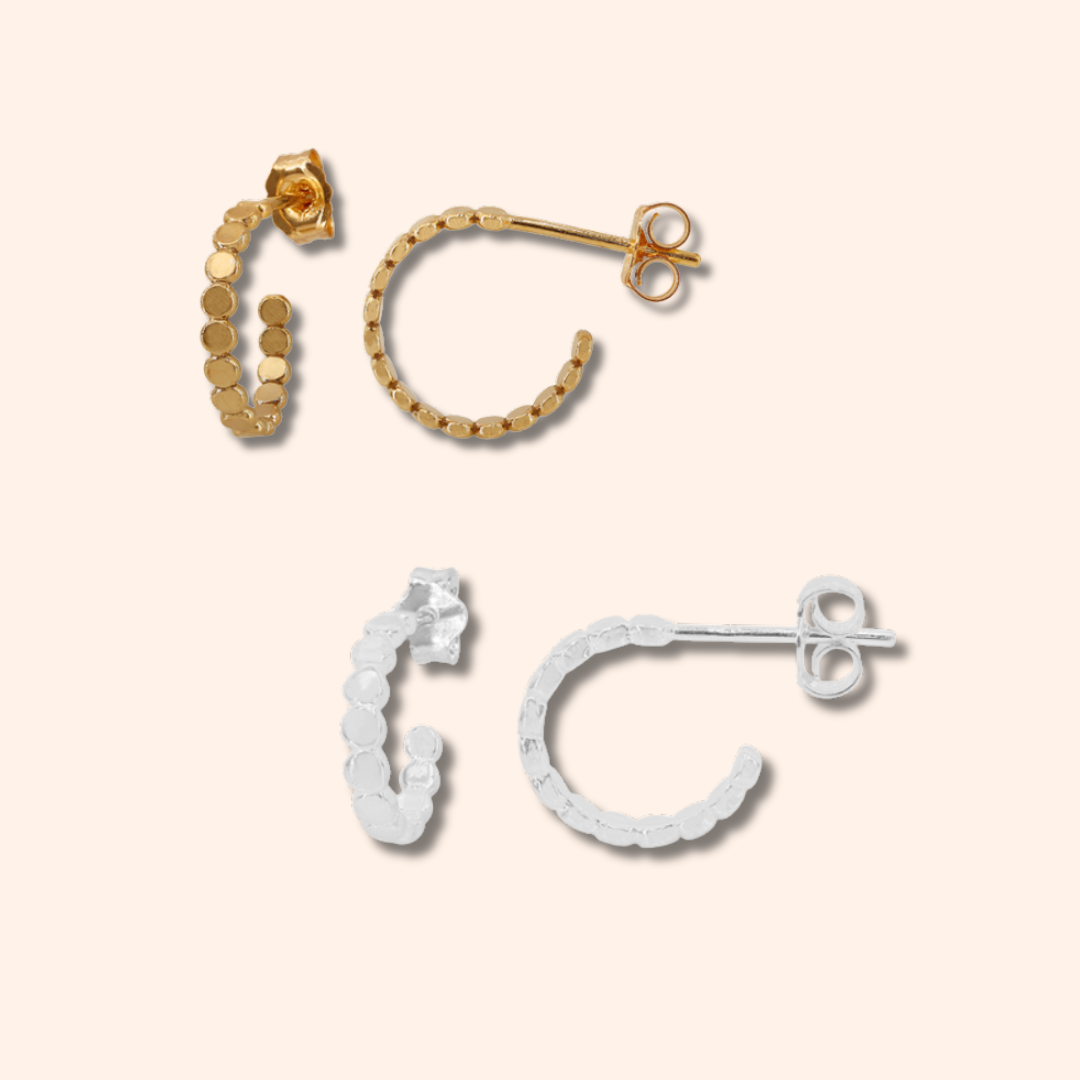 Set of gold and silver hoop earrings on a beige background