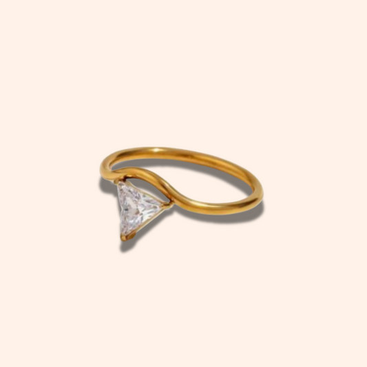 Gold ring with a triangular diamond on a beige background