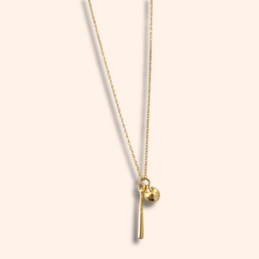 Gold necklace with a small round pendant on a beige background