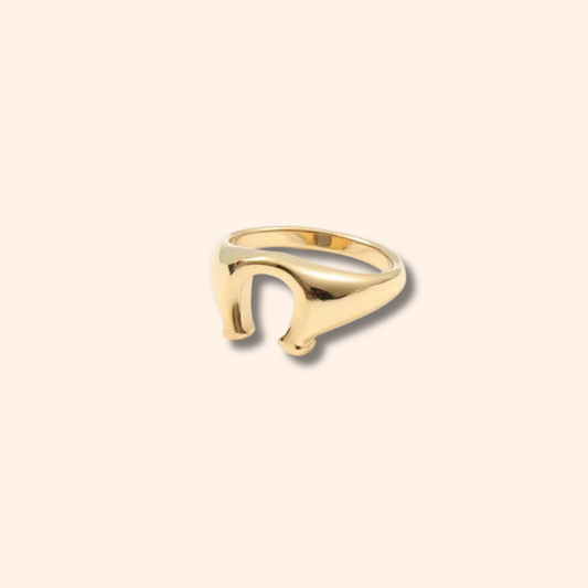 Gold ring with a unique design on a beige background