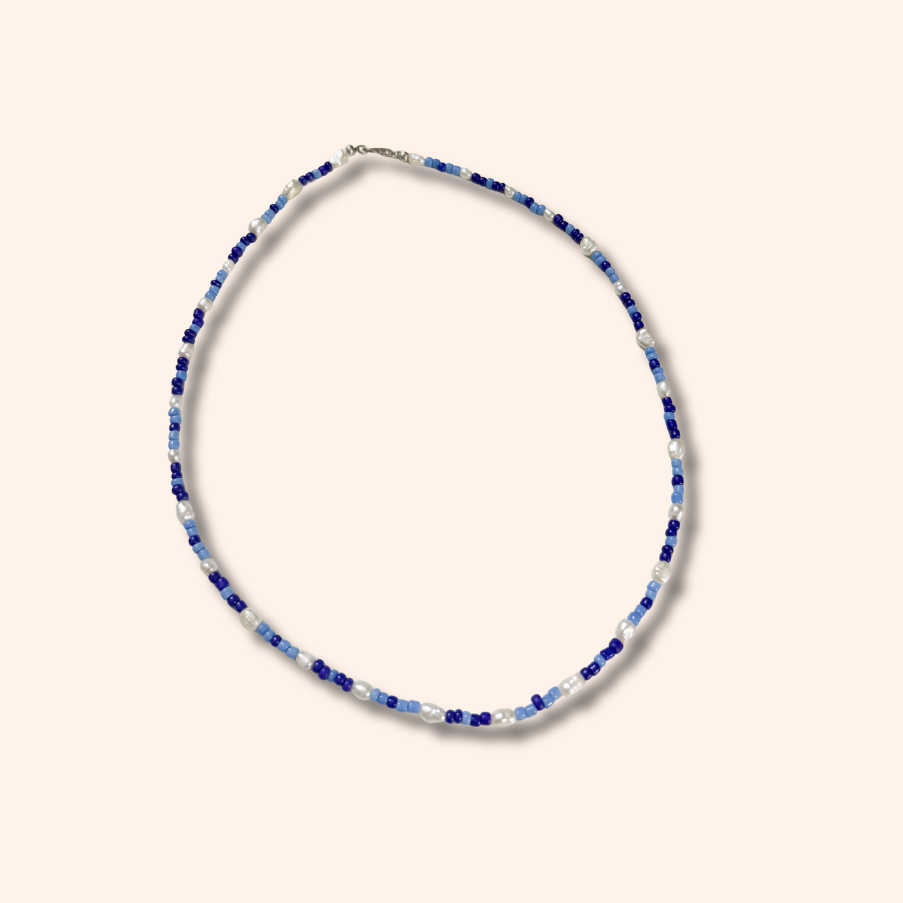 Thin beaded necklace with blue and silver beads on a beige background