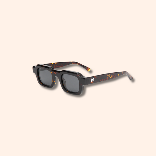 Sunglasses with tortoiseshell frame and dark lenses on a beige background