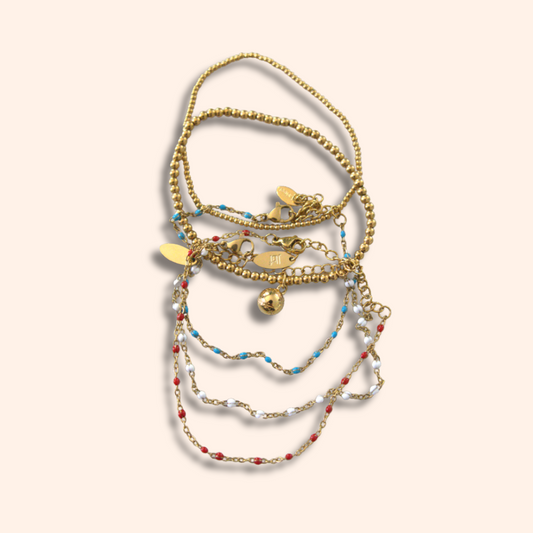 Stack of gold and beaded bracelets on a beige background