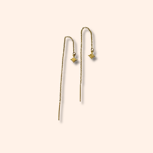 Pair of gold threader earrings on a beige background