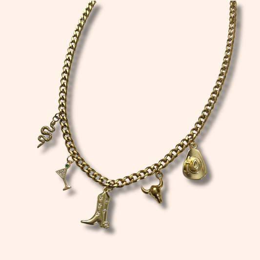 Gold necklace with various charms on a light beige background