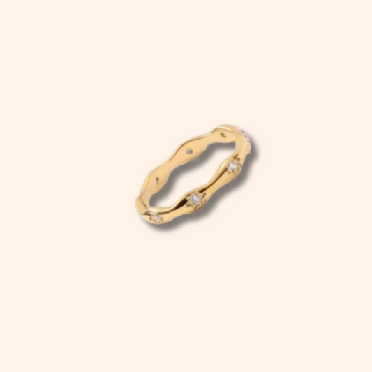Gold ring with small diamonds on a beige background