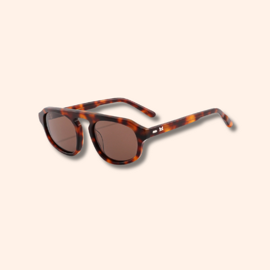 Tortoiseshell sunglasses with brown lenses, shown at an angle on a solid pale beige background.