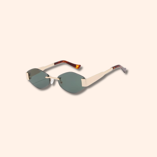 A pair of rimless sunglasses with light beige frames, tortoiseshell temples, and muted green lenses, shown on a solid pale peach background.