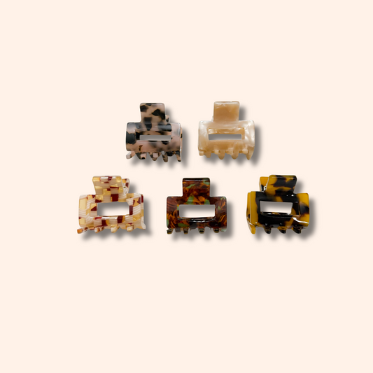 Set of five tortoiseshell patterned hair clips on a beige background