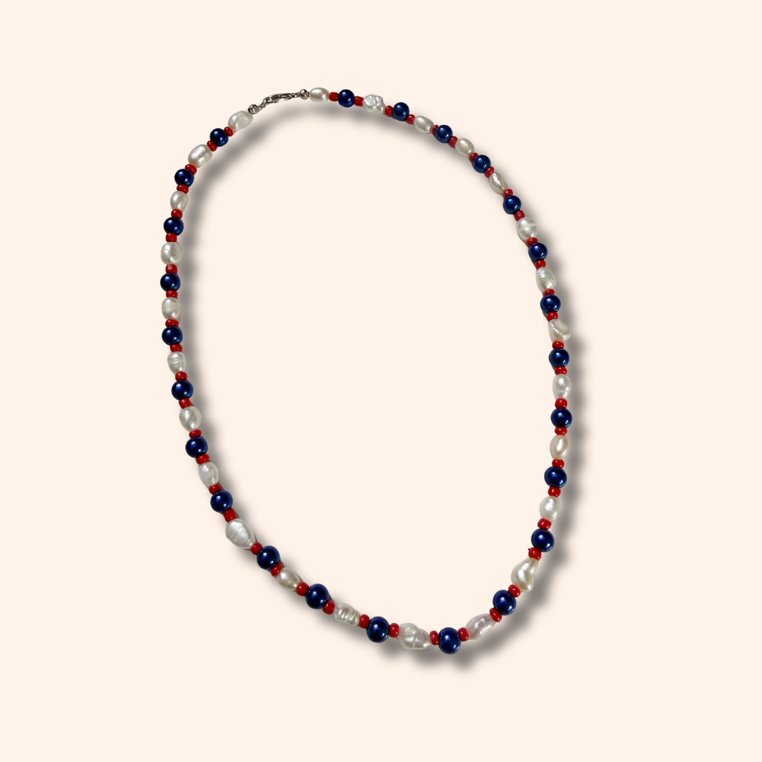 Necklace with red, white, and blue beads on a light pink background