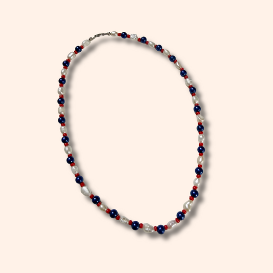 Necklace with red, white, and blue beads on a light pink background